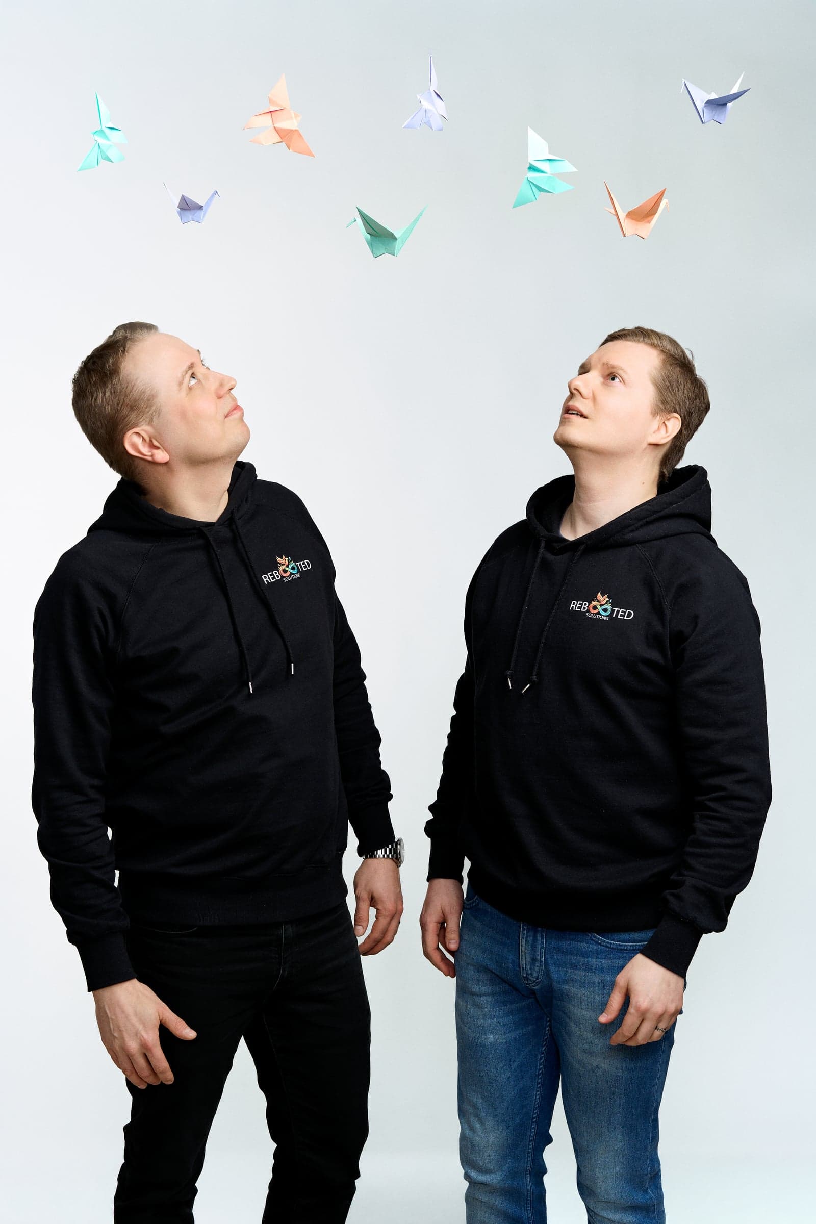 Matti Ilvonen and Henri Parkkonen looking up at origami cranes floating above them — Rebooted Solutions brand photo